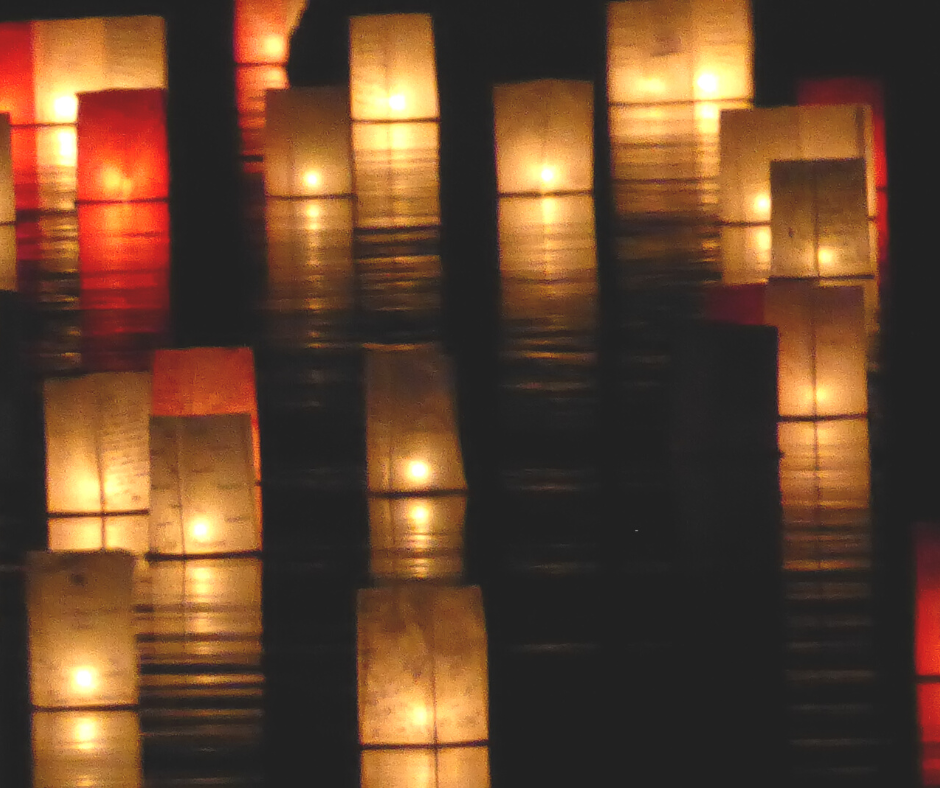 photo showing illuminated water lanterns on the water like they would be at water lantern festival Austin. 